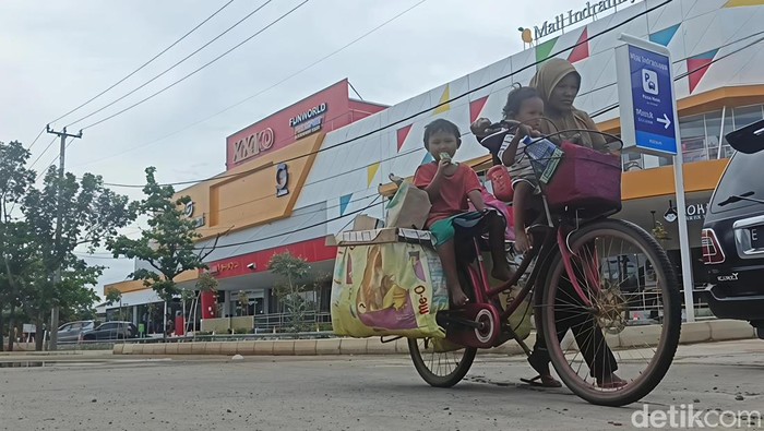 Uniyati menuntun sepada yang diboncengi oleh anak-anaknya.