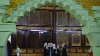 Wisatawan berswafoto dengan latar belakang ukiran ayat-ayat Al-Qur’an di destinasi wisata religi Al Quran Al Akbar, Gandus, Palembang, Sumatera Selatan, Rabu (25/2/2026). ANTARA FOTO/Angga Palguna