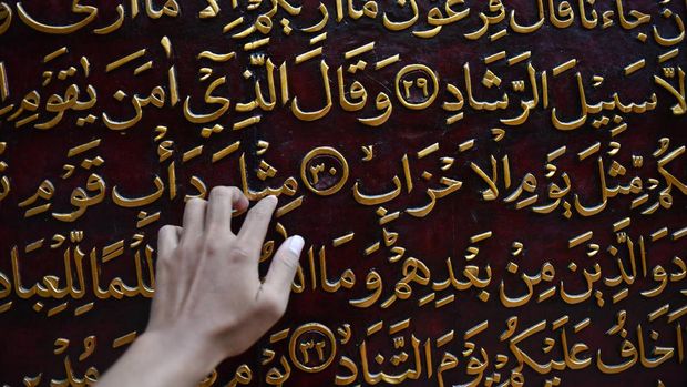 Wisatawan membaca ukiran ayat-ayat Al Quran yang dipajang di Al Quran Al Akbar, Gandus, Palembang, Sumatera Selatan, Rabu (25/2/2026). Al Quran raksasa yang diukir di atas kayu trembesi berukuran 1,77x1,4 meter per lembar dan disusun rapi dengan ketinggian 15 meter tersebut menjadi destinasi wisata religi di Kota Palembang. ANTARA FOTO/Angga Palguna/YU