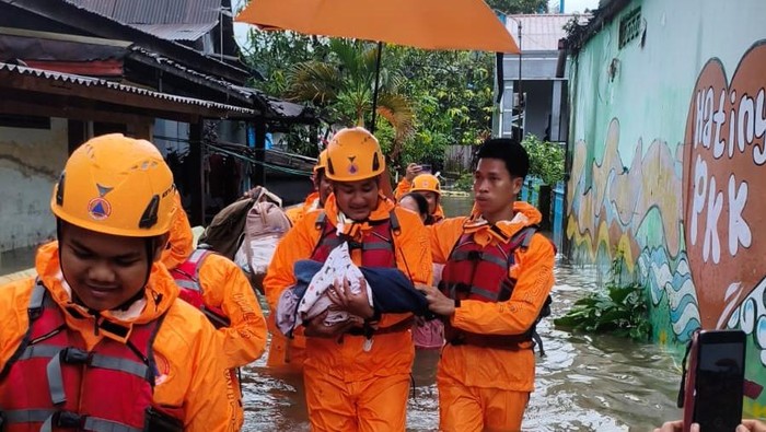 Tim TRC BPBD Makassar saat mengevakuasi bayi korban banjir.