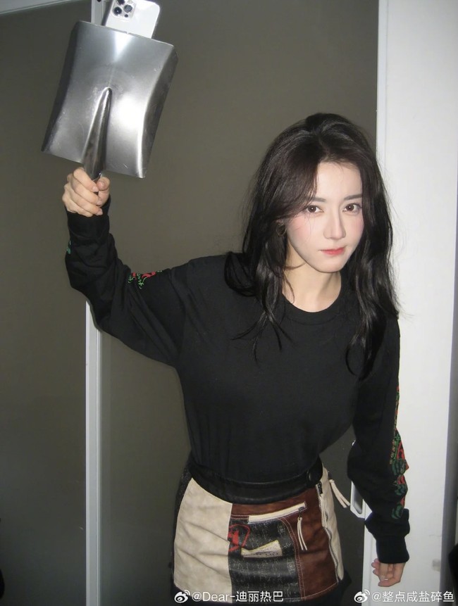 Dilraba Dilmurat tampil dengab outfit hitam long sleeve yang dipadukan rok patchwork. Posenya yang angkat sekop ini pun bikin penampilannya terlihat absurd dan kocak Foto: Dok. Weibo Dilraba Dilmurat