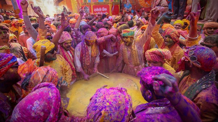 Men daubed in colours throw coloured powder at each other during 