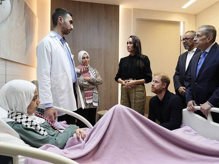 Duke dan Duchess of Sussex berbincang dengan staf medis saat bertemu Maria, seorang korban luka bakar berusia 14 tahun dari Gaza, selama kunjungan ke Rumah Sakit Spesialis di Amman, Yordania.