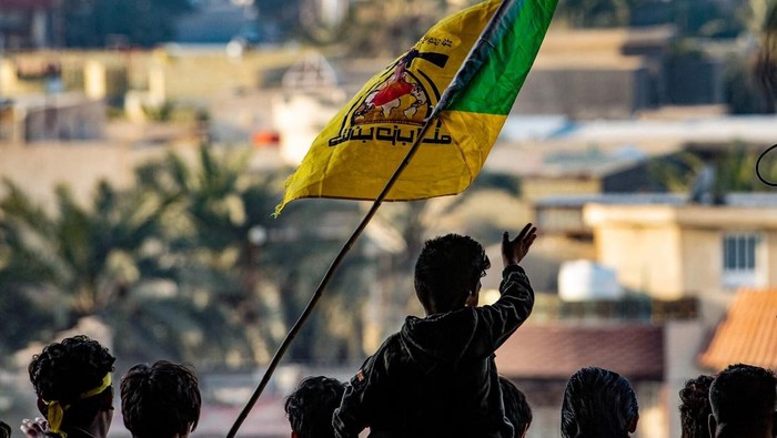 Illustrative: Young men raise the flag of the Iran-backed Kataeb Hezbollah group during commemorations marking the second anniversary of the killing of top Iranian commander Qassem Soleimani and Iraqi paramilitary commander Abu Mahdi al-Muhandis, in 