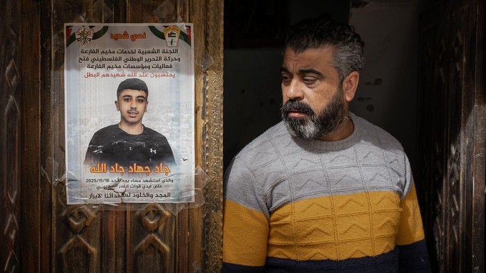 Ayah Jad berdiri di samping poster mengenang putranya di pintu depan rumah mereka. Anakku tidak membahayakan para tentara itu, katanya. (BBC)