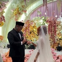 Virgoun tampil mengenakan setelan jas hitam dipadukan kemeja putih dan dasi kupu-kupu. Penampilannya semakin lengkap dengan kopiah hitam yang menutup kepalanya. Sementara Lindi memilih gaun pengantin berwarna putih. Foto: Instagram/@virgoun_/@lindifitriyana