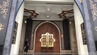 Pintu utamanya terbuka megah dilapisi marmer abu-abu, dipertegas dengan lengkungan berwarna kuning emas. Latarnya terbentang hamparan karpet rumput yang membuat sejuk suasana. Pengunjung dapat duduk santai di atas karpet itu.