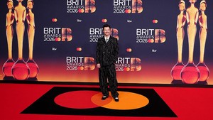 Harry Styles tampak rupawan mengenakan jaket double-breated berbahan boucle dengan motif garis hitam-putih yang dipadukan dengan celana longgar senada. Foto: REUTERS/Isabel Infantes