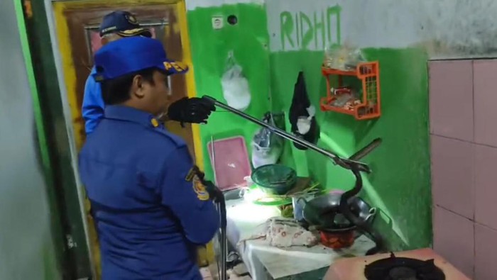 Petugas Damkar saat mengevakuasi ular dari dapur rumah warga