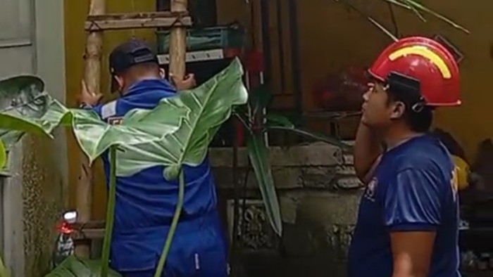 Petugas Damkarmat sektor Srono Banyuwangi berupaya melakukan evakuasi korban terjebak di lantai atap.