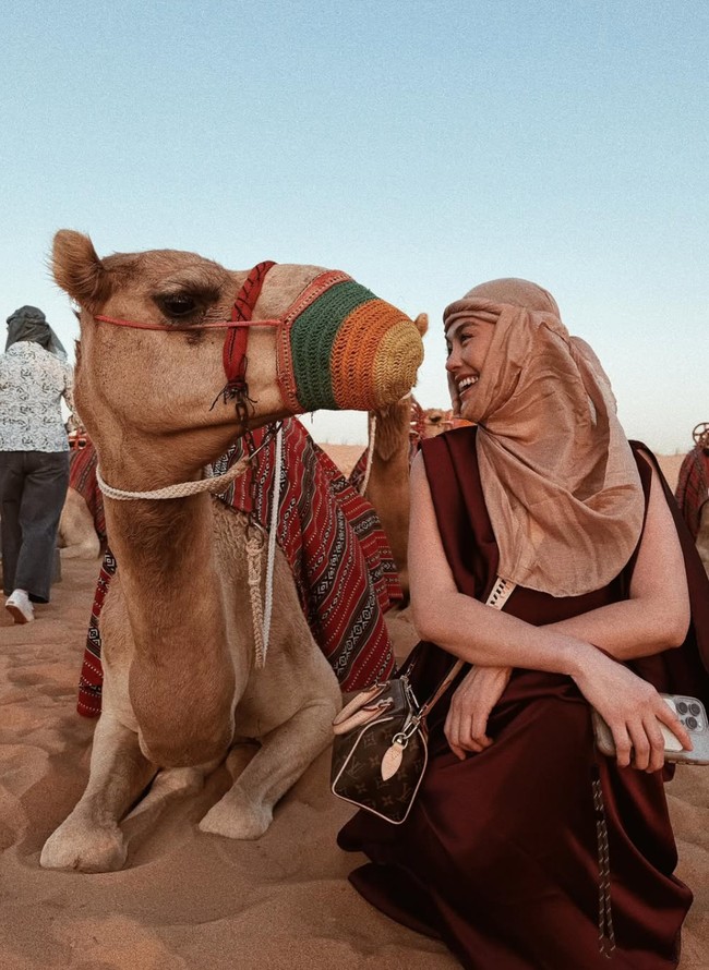 Pamer kebahagiaan selama di sana, pelantun lagu Coke Bottle itu juga berpose berdua dengan unta. Saling menatap, Agnez terlihat tertawa manis. Foto: Instagram/@agnezmo