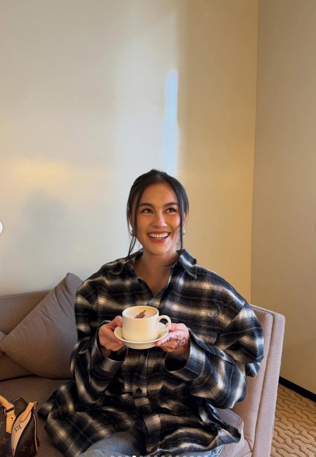 Bergaya santai, Agnez memadukan kemeja kotak-kotak oversized dengan celana jeans biru. Rambutnya tampak simpel dengan hanya diiket kebelakang dan membiarkan sedikit bagian depan rambutnya terurai natural. Foto: Instagram/@agnezmo