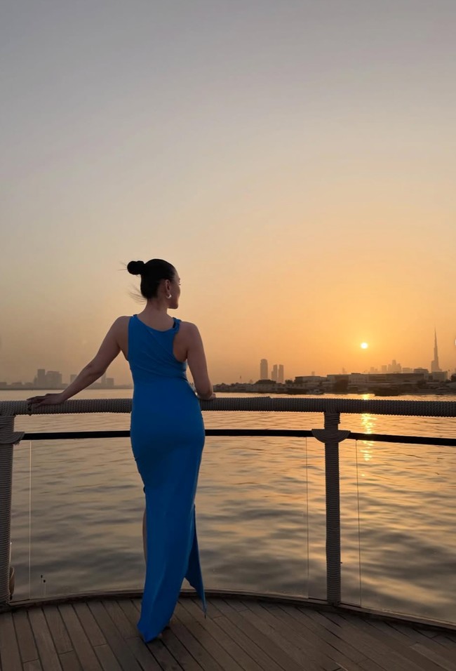 Sambil menikmati sunset, penampilan Agnez dengan dress biru tampak elegan namun tetap simpel. Rambutnya rapi dengan dicepol ke atas. Foto: Instagram/@agnezmo