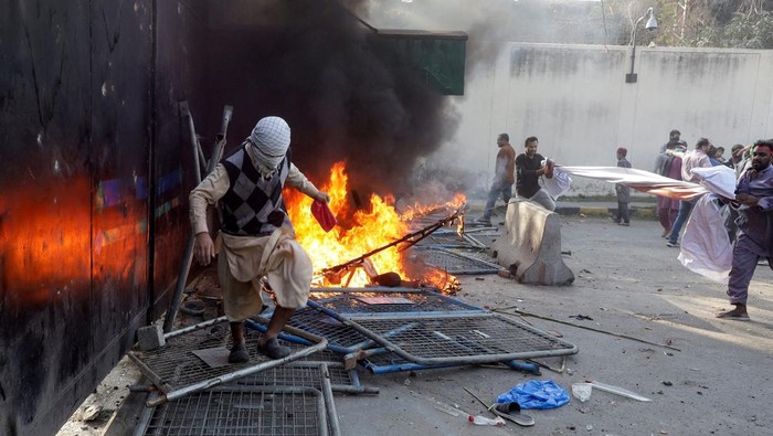 Aksi demonstrasi merespons serangan AS dan Israel di tembok luar konsulat AS di Karachi, Pakistan, Minggu (1/3/2026). (REUTERS/Mohsin Raza)