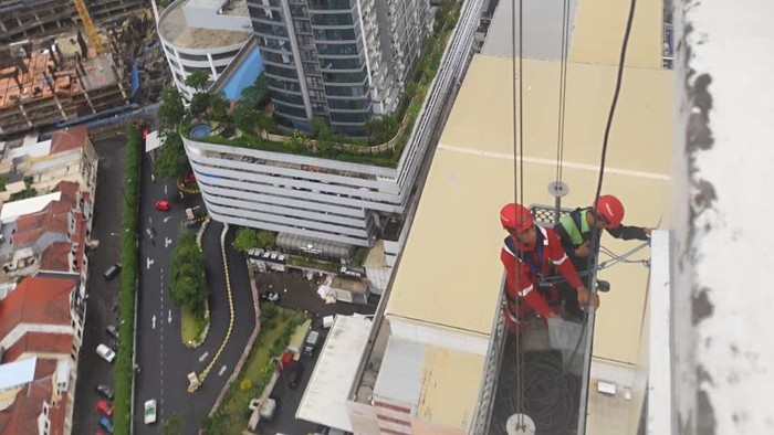 Evakuasi pekerja pembersih kaca yang terjebak saat hujan badai di apartemen Ascott