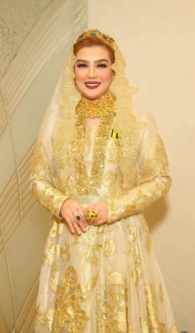Tampil bak ratu, ia mengenakan gaun pengantin penuh payet berwarna emas yang glamor lengkap dengan headpiece yang berkilau. Detail bordir yang rumit pada seluruh busananya menunjukkan selera fashion yang menjadi pusat perhatian. Foto: Dok. Instagram @syarifahsuraidah.