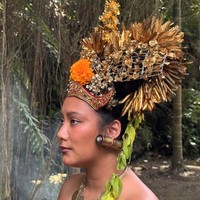 Salah satu yang tak kalah mencuri perhatian adalah mahkota besar berwarna emas yang dikenakan Tara. Hiasan kepala tersebut dipenuhi ornamen bunga dan detail ukiran khas Bali. Dipadukan dengan anting besar serta kalung emas bertumpuk, tampilannya semakin dramatis. Foto: Instagram/@tarabasro