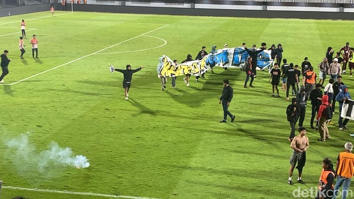Suporter PSM Makassar masuk lapangan dengan melempat flare dan petasan usai laga lawan Persita di Stadion Gelora BJ Habibie.