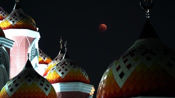 Saat memasuki fase totalitas, bulan tampak berwarna kemerahan fenomena yang kerap disebut sebagai “blood moon”. Pantulan cahaya redup bulan yang tertutup bayangan bumi berpadu dengan siluet kubah-kubah masjid berwarna cerah, menciptakan panorama dramatis yang mengundang decak kagum warga. ANTARA FOTO/Hasrul Said