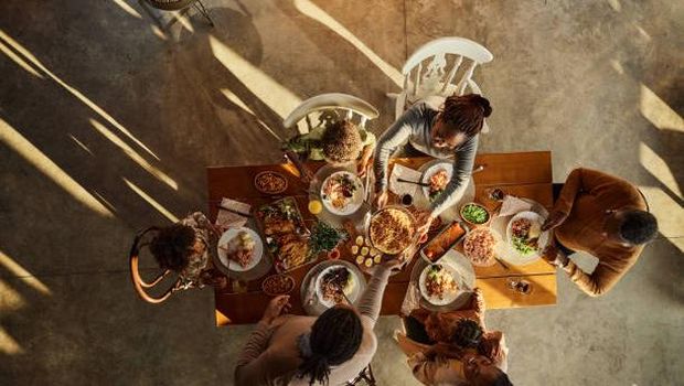 Ilustrasi makan bersama keluarga. High angle view of African American multi-generation family having a meal at dining table. Copy space.