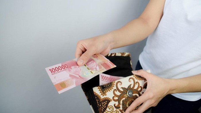 Woman take out from her wallet and Showing 100.000 Indonesian Rupiah Money