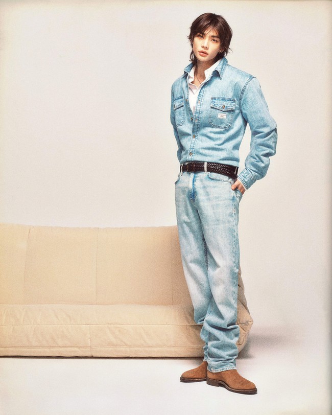 Tren gaya denim on denim ditampilkan Hyunjin dengan pendekatan baru. Padanan klasik kemeja denim dan jeans dibuat lebih modern dengan kemeja putih di dalamnya, plus ikat pinggang hitam bertekstur anyaman sebagai aksen. Foto: Dok. GUESS