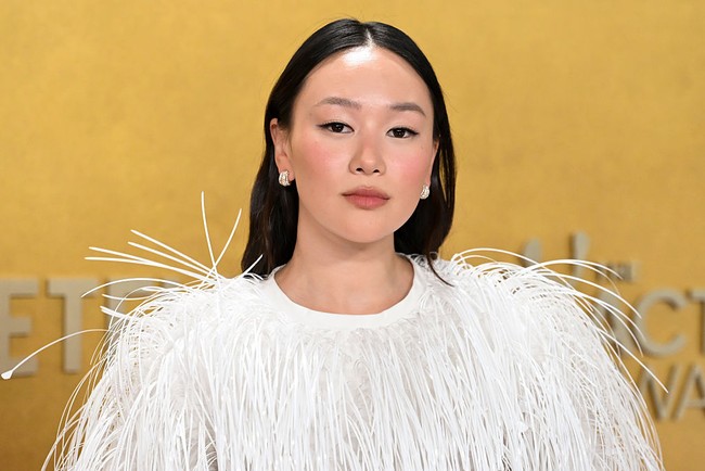 Makeup natural dengan kompleksi glowing, eyeliner hitam tegas, serta lipstik nuansa nude-pink memberi kesan segar. Rambut panjangnya ditata bergelombang ringan dengan belahan tengah, lalu diselipkan di belakang telinga sehingga memberi kesan santai namun tetap rapi. Foto: Deadline via Getty Images/Earl Gibson III