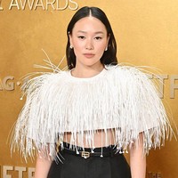 Busana atasan dihiasi aplikasi bulu halus yang menciptakan tekstur dan dimensi pada tampilannya. Tampilan kontemporer ini merupakan koleksi rumah mode Spanyol Balenciaga Spring/Summer 2026. Untuk aksesori, Yerin mengenakan sepatu pumps hitam serta sabuk tipis dengan gesper emas yang membantu menegaskan garis pinggangnya. Foto: Deadline via Getty Images/Earl Gibson III