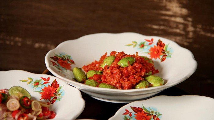 Sambal Petai, a popular condiment of red chili paste with stink (bitter) beans from Central Java. The condiment is plated on old-fashioned crockery with red flowers paintings. It is served together with other popular spicy condiments from several oth