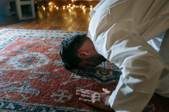 Seorang pria muslim sujud di atas sajadah. Ilustrasi sholat Tahajud.