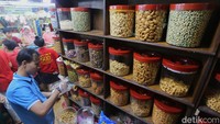 Pedagang kue kering dan kue lebaran mengambil kue dari toples di Pasar Jatinegara, Jakarta, Senin (9/3/2026). Kue kering dijual dengan harga beragam mulai dari Rp 150 ribu per kilogramnya tergantung jenis kue.  