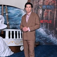Mackenyu, pemeran Roronoa Zoro memilih gaya necis dengan setelan pin-stripe warna mocha dipadu kemeja satin beige dan pantofel. Foto: Getty Images