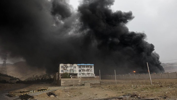 People stand near a destroyed vehicle as smoke rises after a reported strike on Shahran fuel tanks, amid the U.S.-Israeli conflict with Iran, in Tehran, Iran, March 8, 2026. Majid Asgaripour/WANA (West Asia News Agency) via REUTERS ATTENTION EDITORS 