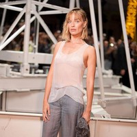 Untuk penampilannya di acara fashion tersebut, Robbie memilih busana yang sederhana namun tetap elegan. Ia mengenakan tank top putih transparan dengan potongan scoop neck yang menonjolkan siluet tubuhnya. Di bagian dalam, terlihat bralette senada yang sedikit mengintip dari balik atasan tersebut. Foto: WWD via Getty Images/WWD