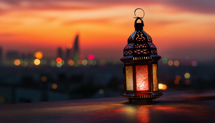 Ornamental Arabic lantern with burning candle glowing at night background. Festive greeting card, invitation for Muslim holy month Ramadan Kareem.