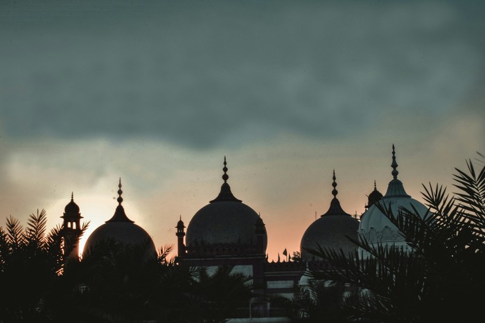 Beberapa kubah masjid dengan latar belakang langit sore.