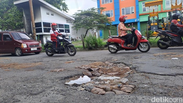 Jalan berlubang yang ditambal warga dengan batok kelapa di Kertomenanggal Surabaya.