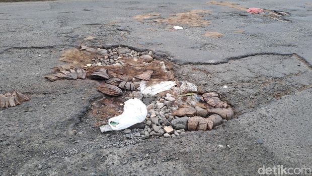 Jalan berlubang yang ditambal warga dengan batok kelapa di Kertomenanggal Surabaya. Jalan berlubang yang ditambal warga dengan batok kelapa di Kertomenanggal Surabaya.