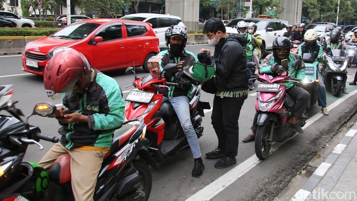 Sejumlah warga menunggu pengemudi ojek online di kawasan Jalan Rasuna Said, Kamis (12/3/2026), di tengah keluhan lamanya waktu tunggu layanan transportasi daring.