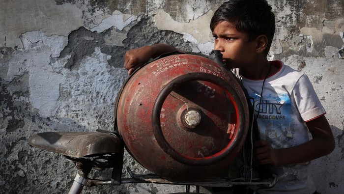 A boy stands next to an empty LPG cylinder tied to a bicycle as he waits outside a gas agency, amid supply disruptions following the U.S.-Israeli conflict with Iran, in Noida, India, March 12, 2026. REUTERS/Bhawika Chhabra     TPX IMAGES OF THE DAY