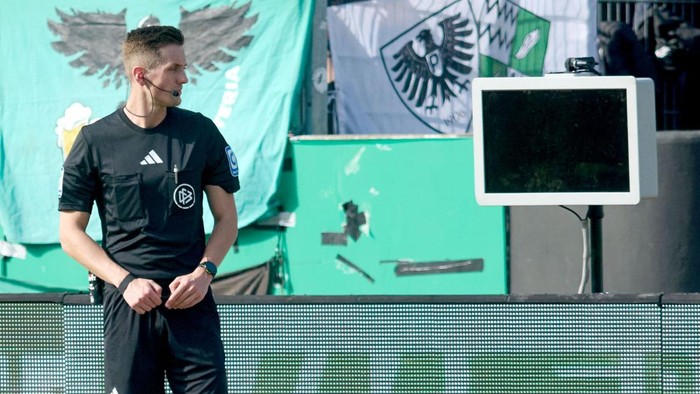 Wasit pertandingan Felix Bickel berdiri di depan layar VAR yang kosong setelah alat itu dicabut.