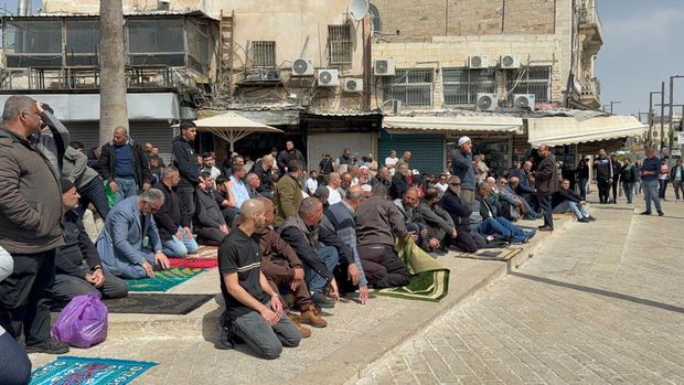 Jemaah muslim salat di luar Masjid Al-Aqsa Jemaah muslim salat di luar Masjid Al-Aqsa pada hari ke-14 penutupan berturut-turut oleh Israel, Jumat (13/3/2026).