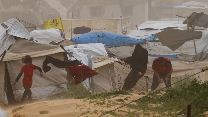 Palestinians walk amid a sandstorm in a tent camp sheltering Palestinians displaced during the two-year Israeli offensive, in Khan Younis in the southern Gaza Strip, March 14, 2026. REUTERS/Ramadan Abed     TPX IMAGES OF THE DAY