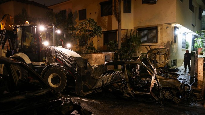 Heavy machinery works near destroyed vehicles at an impact site following an Iranian projectile strike, amid the U.S.-Israeli conflict with Iran, in central Israel, March 13, 2026. REUTERS/Tyrone Siu     TPX IMAGES OF THE DAY