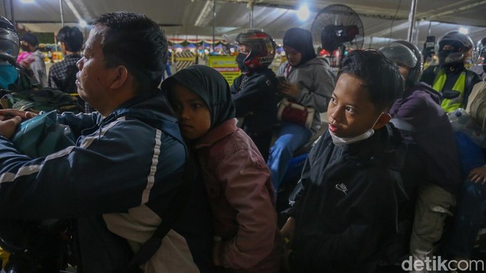 Seorang anak duduk di depan sepeda motor saat keluarga pemudik mengantre di Pelabuhan Ciwandan, Minggu (15/3/2026).