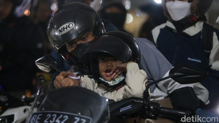 Seorang anak duduk di depan sepeda motor saat keluarga pemudik mengantre di Pelabuhan Ciwandan, Minggu (15/3/2026).
