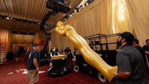 Tim pekerja menggunakan derek untuk menegakkan patung Oscar berwarna emas di pintu masuk teater tempat digelarnya Academy Awards. Foto: REUTERS/Mike Blake