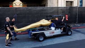 Pekerja memindahkan patung raksasa menyerupai trofi Academy Awards di area karpet merah menjelang acara penghargaan film tahunan tersebut di Los Angeles, California, AS. Foto: REUTERS/Caroline Brehman