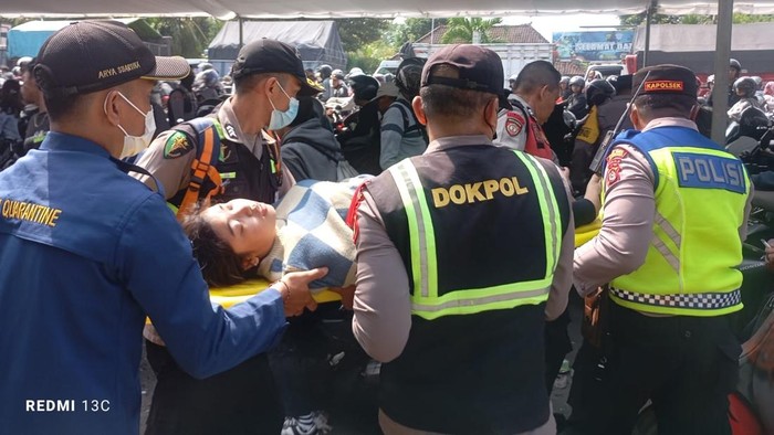 Petugas saat melakukan evakuasi salah satu pemudik yang mengalami kelelahan akibat terlalu lama mengantre menuju Pelabuhan Gilimanuk (Polres Jembrana)