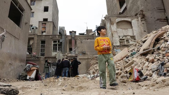 Seorang anak laki-laki berdiri di dekat sebuah rumah yang rusak akibat serangan, di tengah konflik AS-Israel dengan Iran, di Teheran, Iran, 15 Maret 2026. (Reuters)